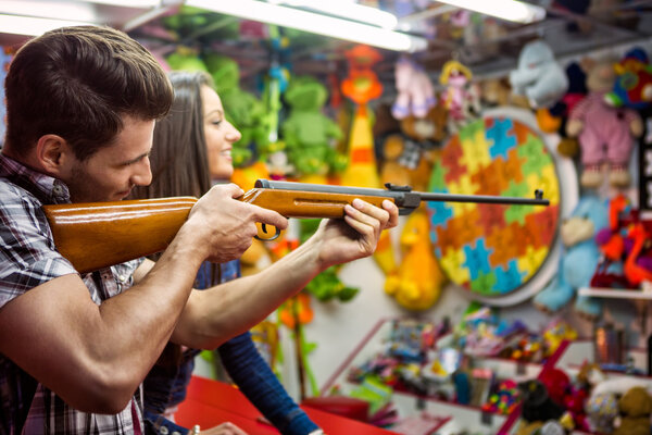 couple playing shooting games while visiting an amusement park