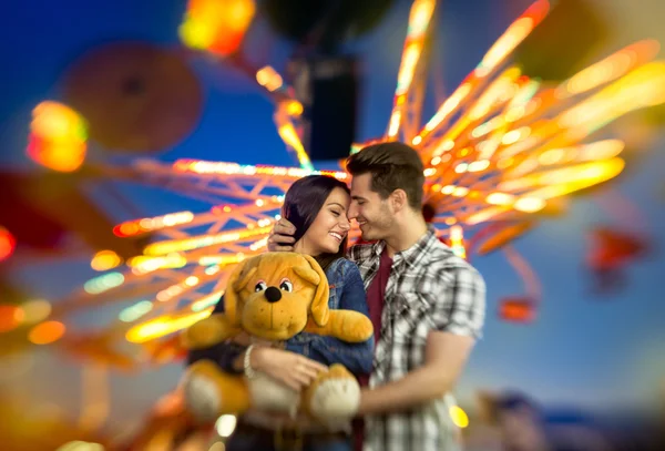 Amor casal com carrossel colorido no fundo — Fotografia de Stock