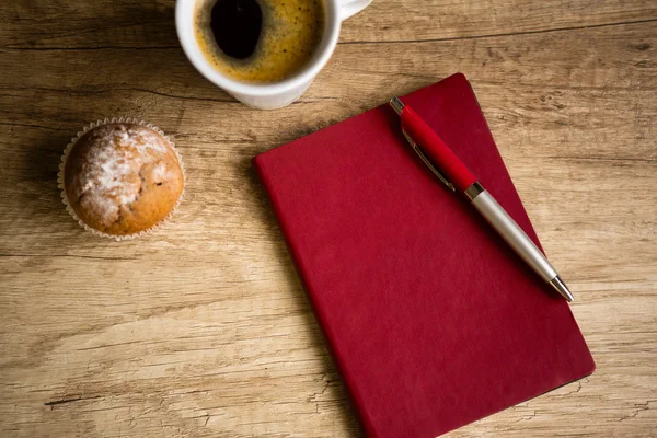 Красная тетрадь с ручкой на деревянном столе — стоковое фото