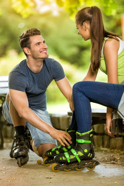 Paar zetten in lijn schaatsen in park — Stockfoto