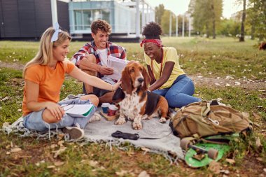 Üç öğrenci. Parkta öğrenciler. Kitap okuyan gülümseyen üniversite öğrencileri. 