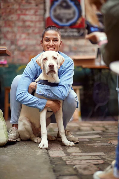 Güzel beyaz bir kadının portresi. Köpeğine sarılıyor, gülümsüyor.