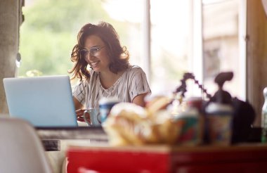 Genç bir kadın ofisteki hoş bir atmosferde dizüstü bilgisayarla çalışıyor.