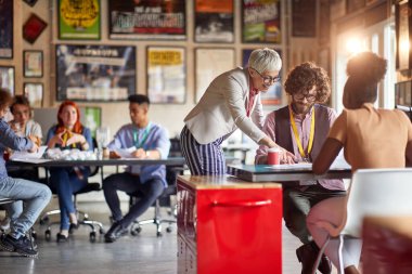 Farklı yaş, ırk ve cinsiyet olarak iki gruptan insanlar açık uzay ofisinde birlikte çalışıyorlar.