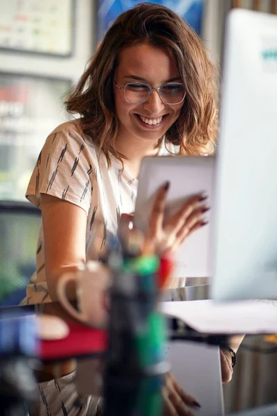 若い女性がオフィスの快適な雰囲気の中で作業中にタブレットを使用しています — ストック写真