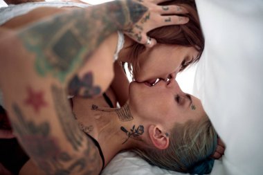 Hipster lezbiyen çift yatakta oynaşıyor.