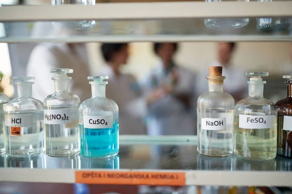 Bottles with different chemicals on the shelf in a sterile laboratory environment. Science, chemistry, lab, people