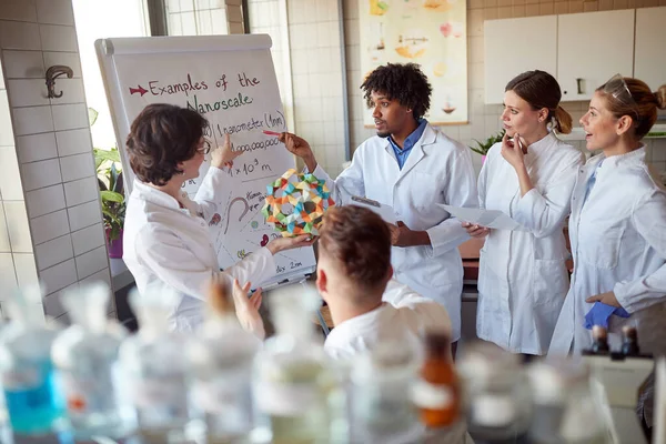 Young chemical students carefully follow a lecturer in the university laboratory in a working atmosphere. Science, chemistry, lab, people