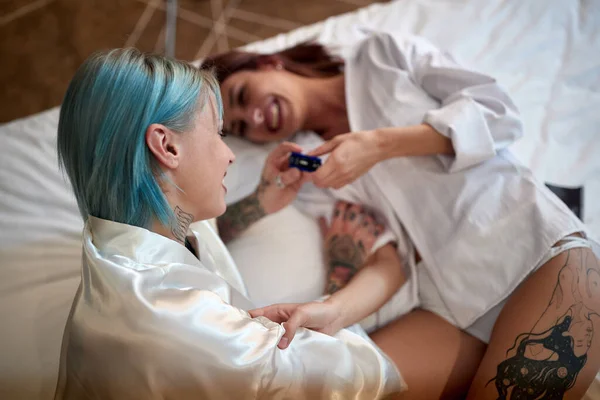ベッドの中でリラックスした雰囲気の中で寝そべっている若い幸せなレズビアンカップルは 正の妊娠検査に興奮しています Lgbt — ストック写真