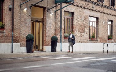 Genç işadamı şehirde yürüyor. Yolda bir adam var. 