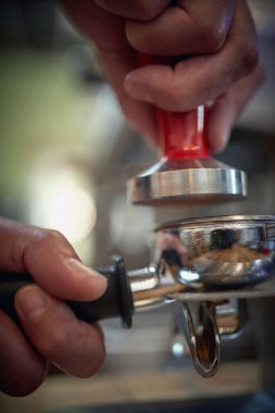 Bir espresso için kokulu ve aromatik öğütülmüş kahveye basan barmenin ellerine yakından bakın. Kahve, içecek, bar.