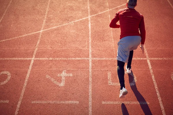 在体育场的一个美丽的日子里 一个年轻人正在赛马场上练习低速起跑 运动员 — 图库照片
