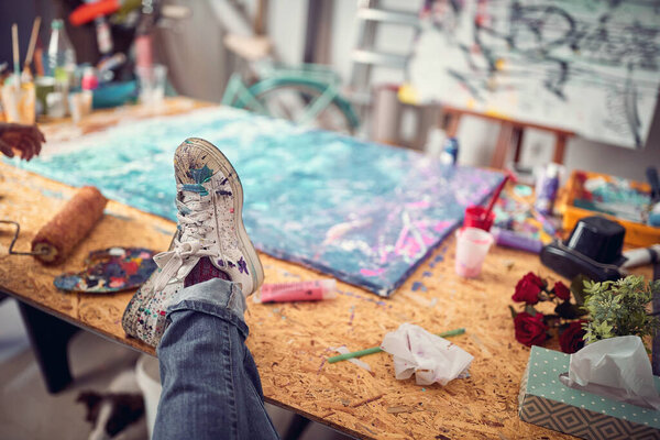 Fun leisure.artist sitting and feet dirty with multicolor paint in studio.