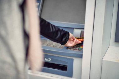 Sokakta para makinesi kullanan bir kadının yakın çekimi. Yürüyüş, ATM, şehir