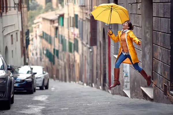 Young Girl Yellow Raincoat Umbrella Jumping Street While Walking City — Stock Photo, Image