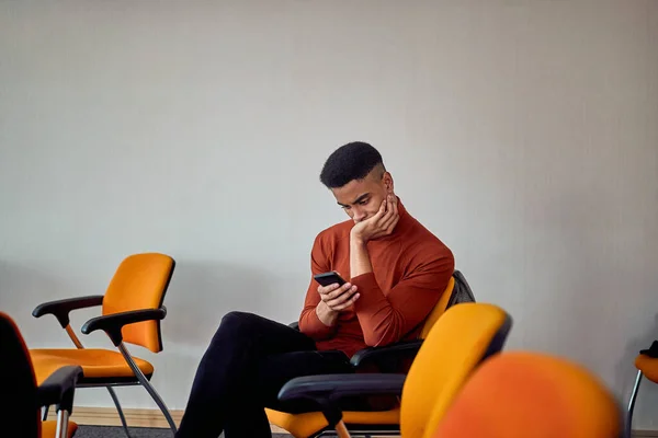 Ung Afro Amerikansk Man Sitter Kontoret Och Ser Orolig Mobiltelefon — Stockfoto