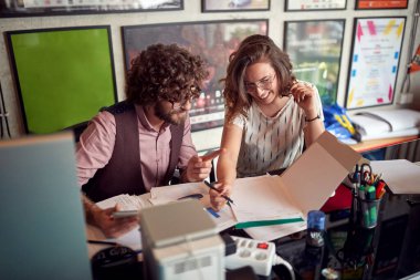 İki genç meslektaşı ofiste çalışırken bazı notlar okuyorlar.