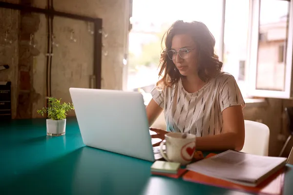 Uma Jovem Mulher Está Trabalhando Laptop Enquanto Está Sentada Mesa — Fotografia de Stock