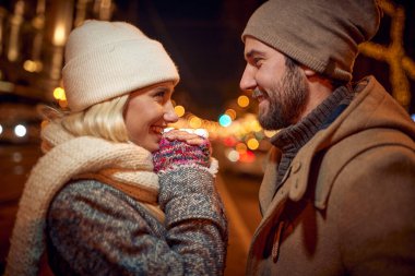 Genç aşık bir çift sokakta sarılıp gülümsüyor.