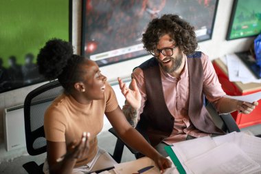 Genç meslektaşlar ofiste hoş bir ortamda çalışırken güzel bir konuşma yapıyorlar.