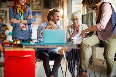 Bir grup iş arkadaşı ofisteki hoş bir atmosferde bazı belgeleri inceliyor.