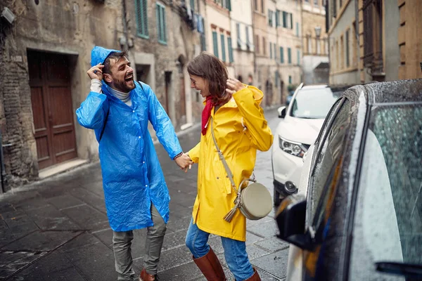 Young Cheerful Couple Raincoats Having Good Time While Running Away — Stock Photo, Image