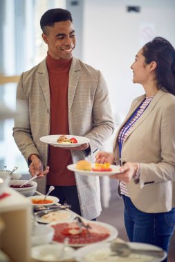 Genç bir adam, bir iş konferansı sırasında rahatlamış bir atmosferde öğle yemeği yerken bayan meslektaşıyla sohbet ediyor. İş, insanlar, toplantı, şirket.