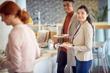 Yemek vakti. Adam ve gülümseyen kadın ofis kafeteryasında yemek yiyorlar.