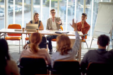 Genç bir işadamı konferans odasındaki rahat bir atmosferde konferans sırasında katılımcının sorularına cevap veriyor. İş, insanlar, şirket.