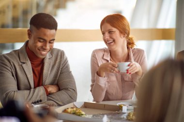 Genç iş arkadaşları iş yerinde öğle yemeğinden sonra arkadaşça bir atmosferde sohbet ediyorlar. İş, insanlar, şirket.