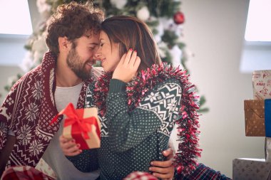 Erkek, romantik kadını öperken ona Noel hediyesi verir.