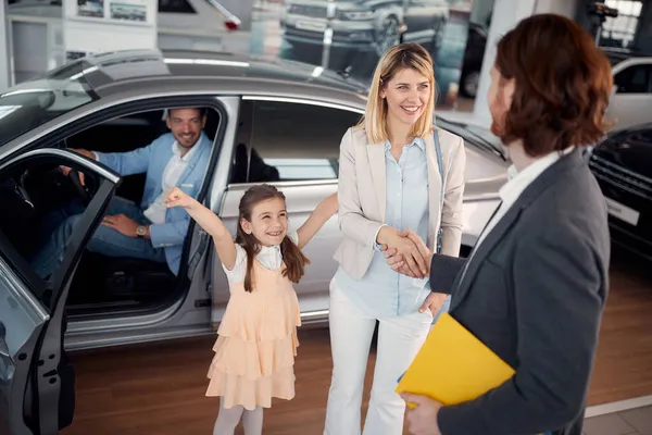 車のディーラーは 新しい車を購入するために手の女性を振る — ストック写真