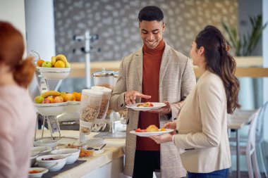 Genç bir adam, bir iş konferansı sırasında rahatlamış bir atmosferde öğle yemeği yerken bayan meslektaşıyla dostça bir konuşma yapıyor. İş, insanlar, toplantı, şirket.