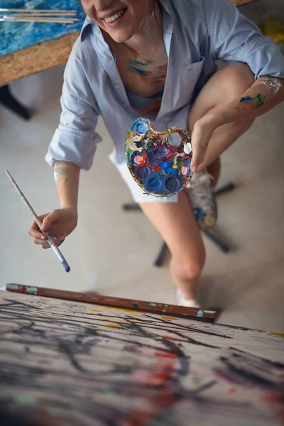 一位年轻性感迷人的女画家坐在画架前 在工作室的轻松氛围中创作新画 工作室 — 图库照片