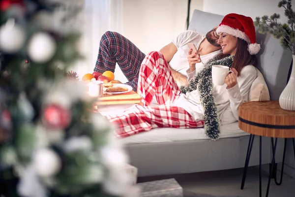男と笑顔女性でクリスマス朝テキストメッセージでザベッド — ストック写真