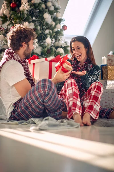 Romantic young man and woman sharing Christmas Gifts at Home.