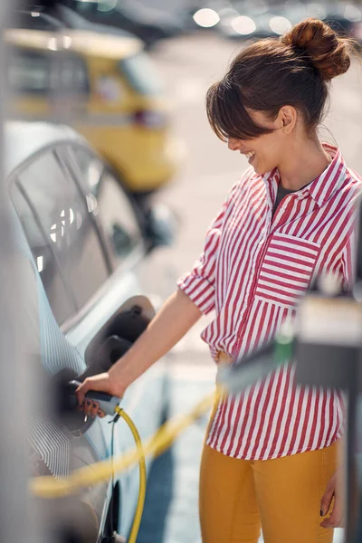 白人妇女在加油站给她的电动车充电 — 图库照片