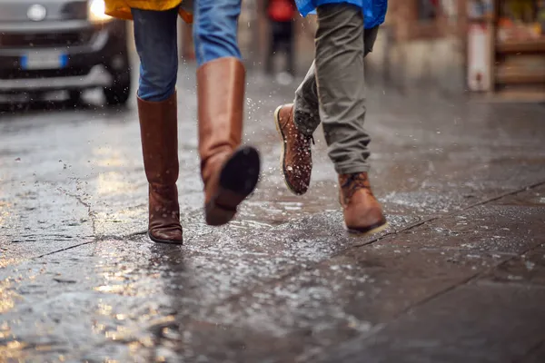 一对年轻夫妇的特写镜头和他们的腿是如何在雨中匆忙地走在城市里的 — 图库照片