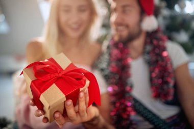 Evde şenlikli bir ortamda birlikte harika vakit geçiren genç bir çiftin yılbaşı hediyesinin yakın çekimi. Noel, ev, ilişki, hediyeler