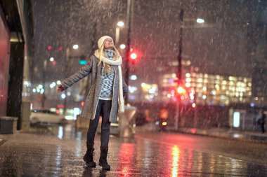 Güzel beyaz kadın sokakta kar taneleri yakalıyor.