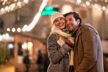 Genç ve neşeli bir çift şehrin güzel bir gecesinde Noel ışığı altında dikiliyor. Noel, yeni yıl, tatil, aşk