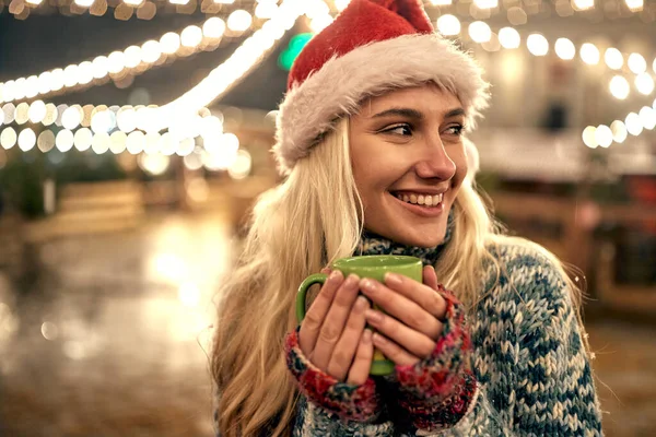 Noel Baba Şapkalı Genç Bir Kadın Noel Panayırında Sıcak Çay — Stok fotoğraf