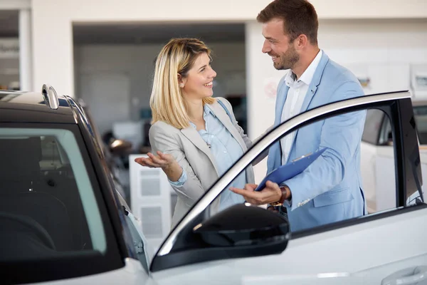 女の子は都市のディーラーで新しい車を購入し セールスマンと話をする — ストック写真