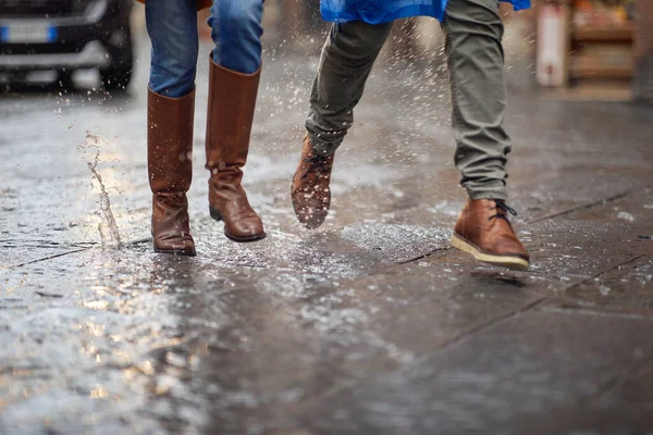 一对年轻夫妇在城市里的雨中匆忙地走着 他们的腿被紧紧地绑住了 — 图库照片