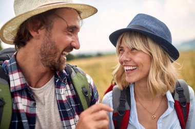 Güneşli bir günde çayırda yürürken genç ve mutlu bir çiftin yakın çekimi. Yürüyüş, doğa, ilişki, birlikte
