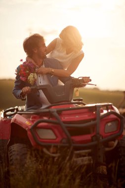 Romantik genç çift Sunset Dörtlü ATV aracında.