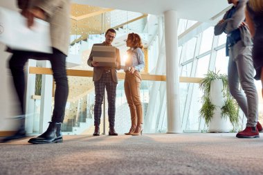 Bir iş kadını koridorda hoş bir atmosferde dizüstü bilgisayar tutan genç bir erkek arkadaşıyla sohbet ediyor. İş, insanlar, şirket.