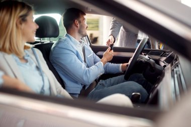 Çift, yeni bir arabanın anahtarlarını bir satış müdüründen alır.