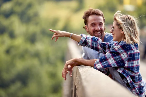 若い笑顔のカップル一緒に橋の上で美しい瞬間を共有する 女性の距離を指している ライフスタイルの概念 — ストック写真