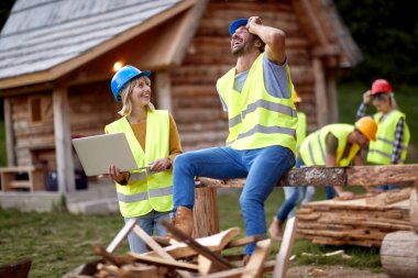Mühendis kadın mühendis ahşap çerçeve şantiyesini kontrol ediyor.